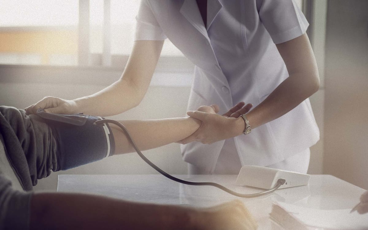 A nurse measures a patient's blood pressure with a cuff on his or her arm.