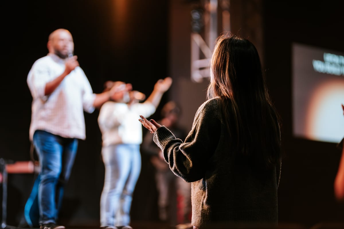 A woman raises her hands in worship during a church service