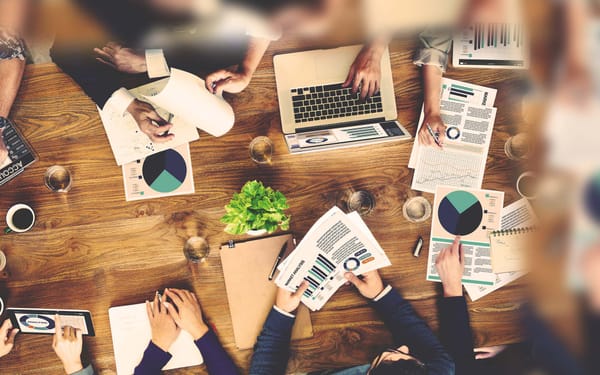 A group of people sit at a table with charts and graphs.