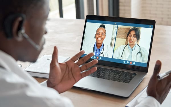 A man speaks to two health professionals through a video call applicaiton on a laptop.