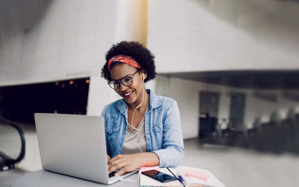 A woman sits at a desk in front of a laptop.