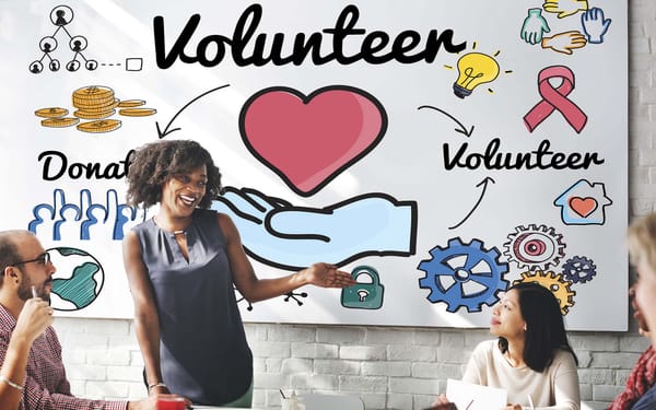 A woman stands in front of a whiteboard that has the words Volunteer and Donate written on it.