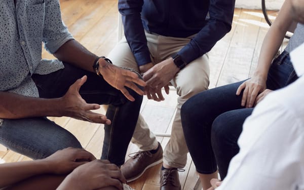 A group of people sit in a circle during a therapy session.