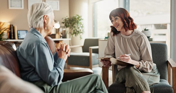 Psychologist chats with senior woman in consultation.