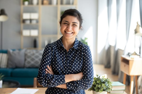 Smiling young woman standing and looking at camera with arms crossed.