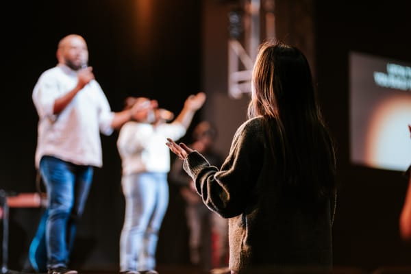 A woman raises her hands in worship during a church service